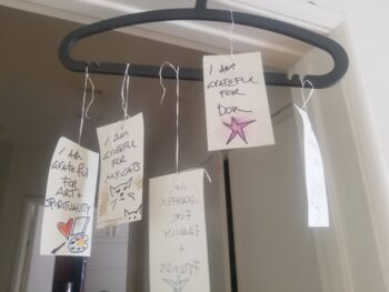 hanger with pieces of paper with notes of gratitude hanging in a doorway